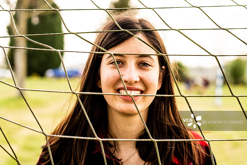 年轻女人在公园球网后微笑的肖像图片素材
