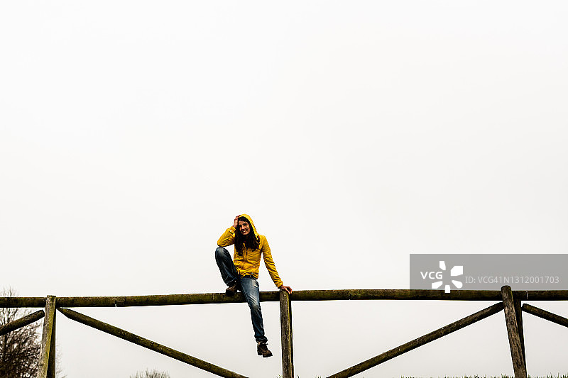 坐在木栅栏上的快乐年轻女人图片素材