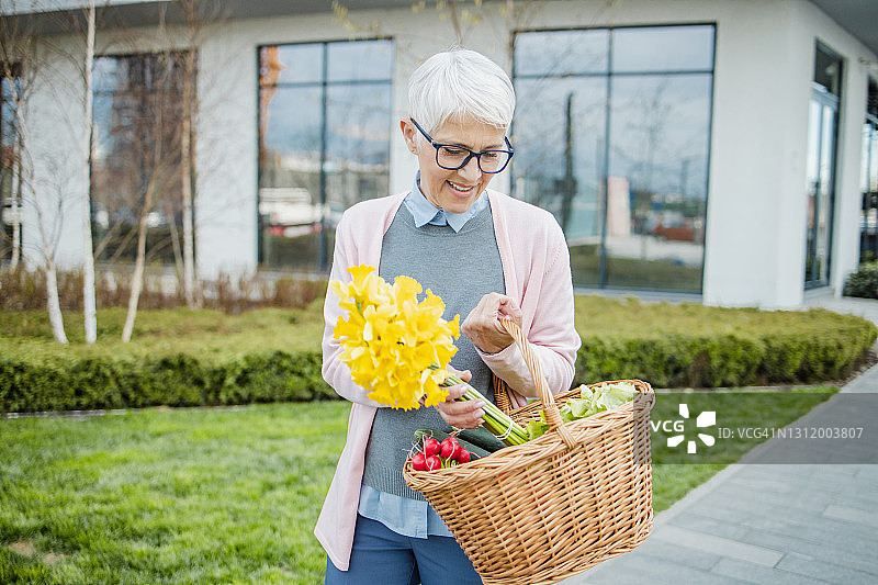 提着装满杂货的篮子走在街上的老年妇女肖像图片素材