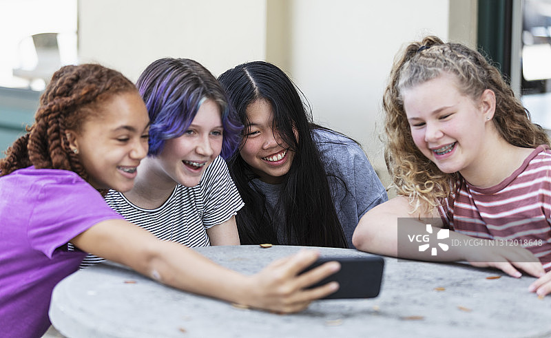 四个少女在用手机看视频图片素材
