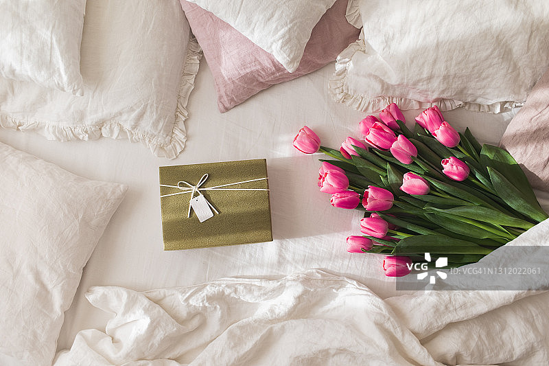 白色亚麻床上放着一束郁金香的礼品盒图片素材