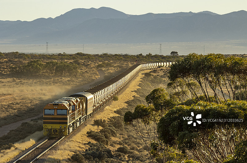 阳光洒在铁矿列车上，以山脉为背景图片素材