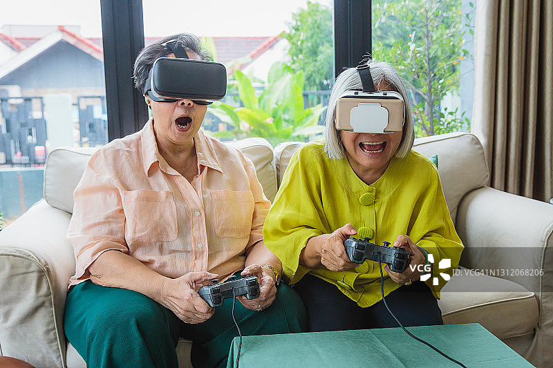 亚洲老年妇女朋友在家中客厅一起玩VR游戏图片素材
