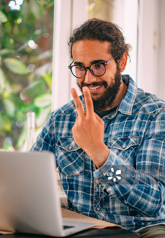 年轻男人在笔记本电脑上进行手语视频通话图片素材