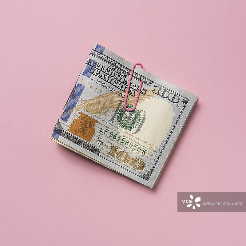 粉色背景上的百元美钞折叠纸币图片素材