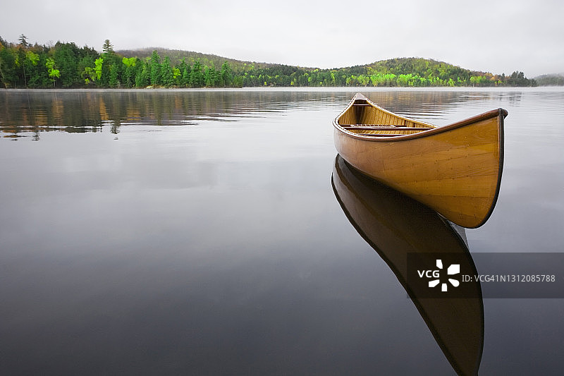 美国纽约州萨拉纳克湖，漂浮在平静的上萨拉纳克湖上的木制独木舟图片素材