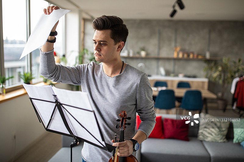 小提琴家站在乐谱架前在家演奏小提琴图片素材