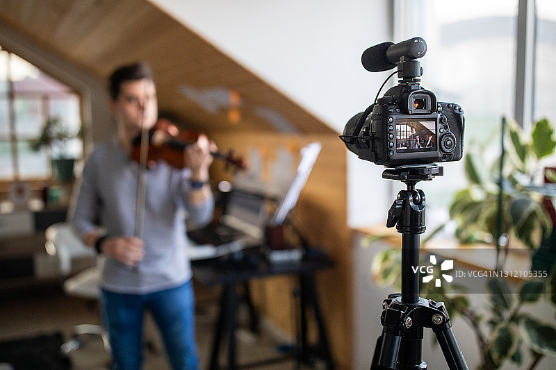 年轻小提琴手在家录制小提琴演奏视频图片素材