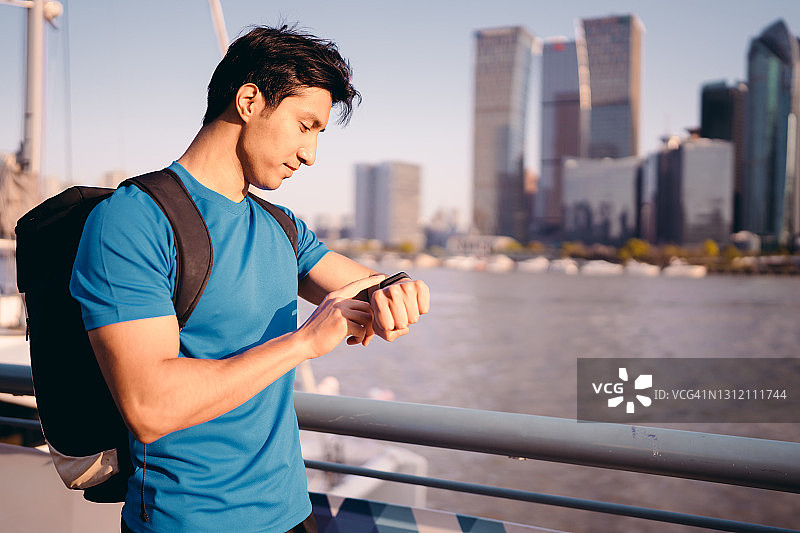 在河边训练后检查健身追踪器数据的健壮年轻运动员图片素材