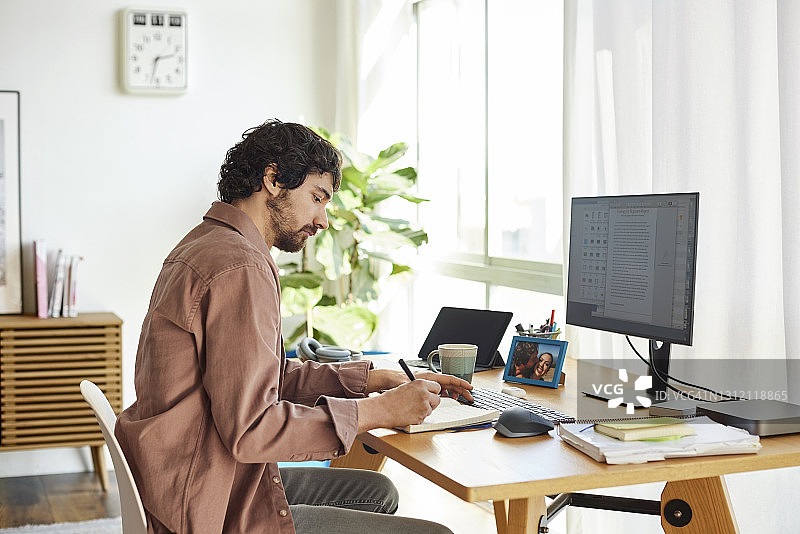 在家办公的男自由职业者在书上写作图片素材