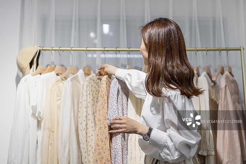 在现代女装店工作的快乐亚洲女企业家肖像，年轻的中国女店主或顾问拿着时装图片素材
