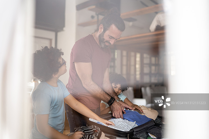 孩子们帮助父亲在家打包行李箱图片素材