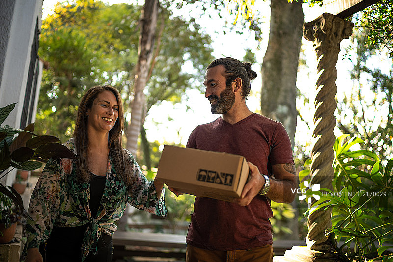 夫妇搬着箱子走进家门图片素材