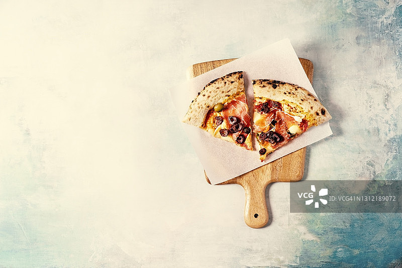 蓝色背景下砧板上的披萨切片图片素材