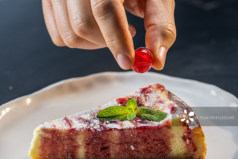 男人手在蛋糕上加糖渍樱桃特写图片素材
