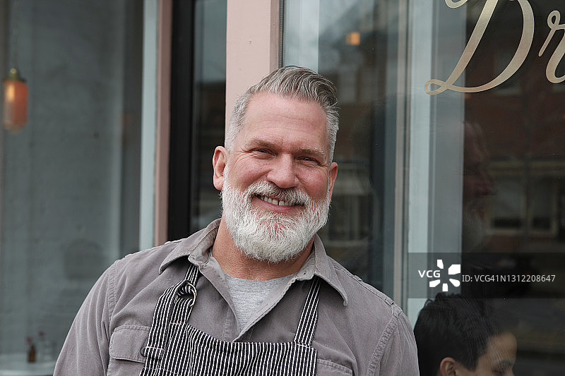 在酒吧入口外，看着镜头的年长男人肖像图片素材