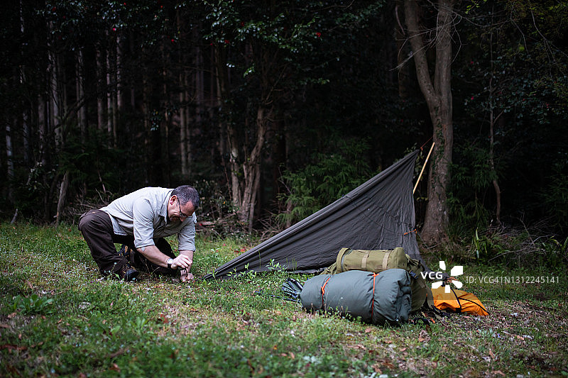 男子在树林里搭建简易住所图片素材