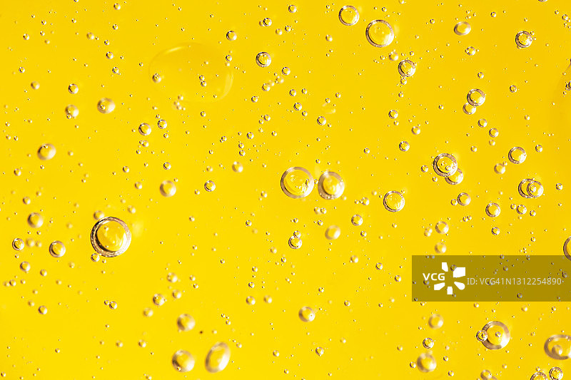 有机透明凝胶或保湿乳液的质地，在明亮的黄色背景上涂抹了许多气泡。护肤化妆品概念。2021年流行色。特写和扁平风格图片素材