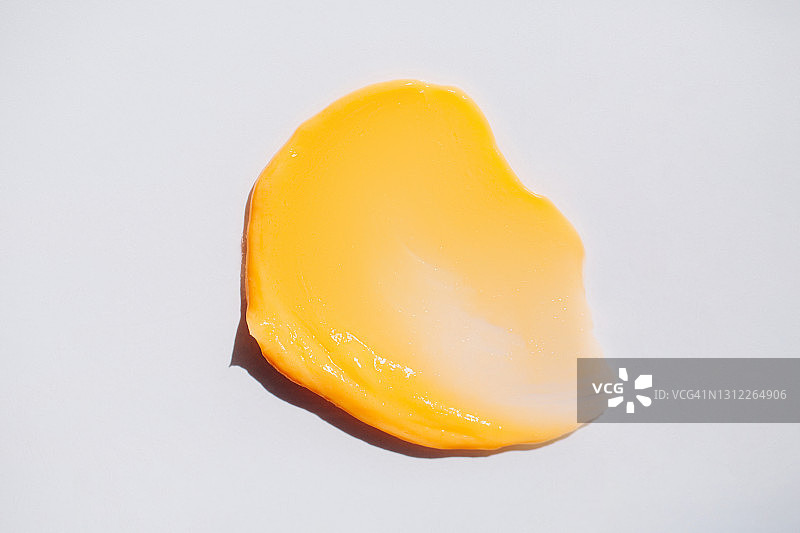 白色背景上鲜橙色乳霜的纹理涂抹，扁平风格，化妆品banner，年度潮流身体护理概念图片素材