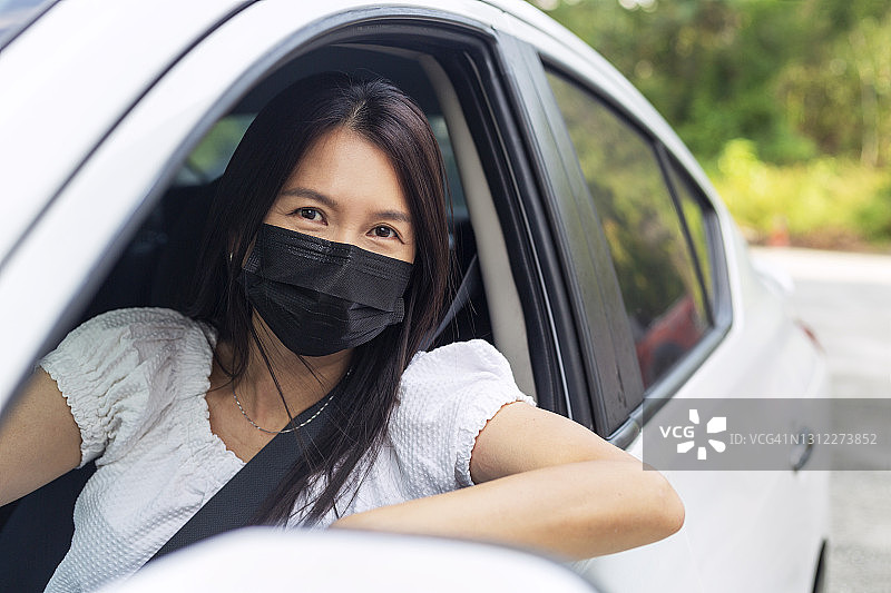 戴防护口罩的亚洲女子在开车图片素材