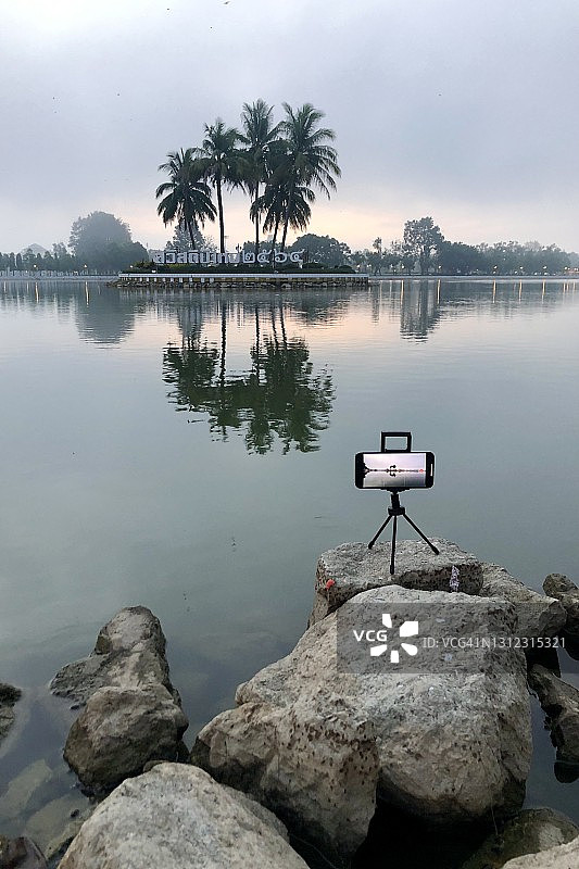 三脚架上的手机拍摄湖中小岛晨雾（达信玛哈拉特公园，尖竹汶府）图片素材
