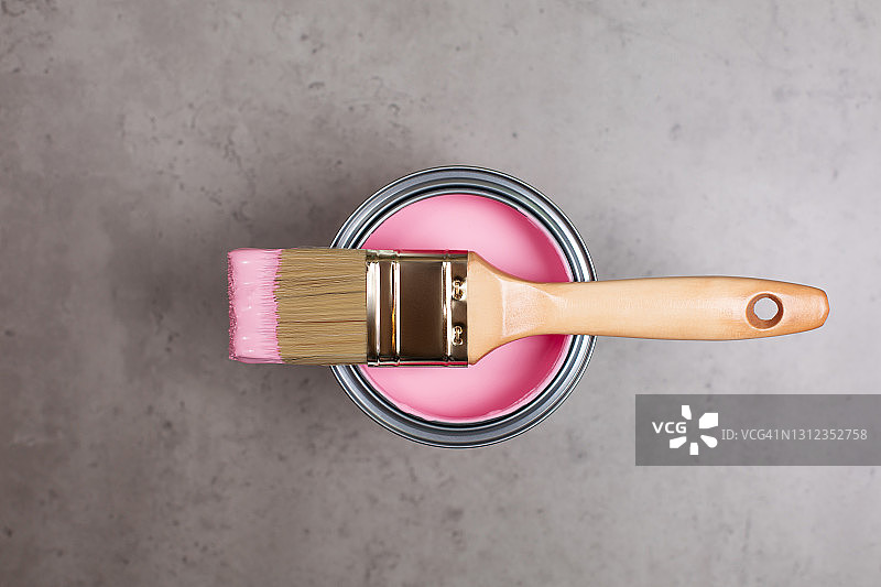 混凝土背景上的粉色颜料桶和画笔。扁平风格特写图片素材