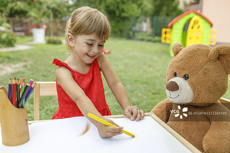 快乐的儿童在画画，对着泰迪熊微笑图片素材