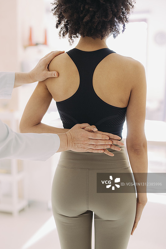 女性背部和医生检查的手部特写图片素材