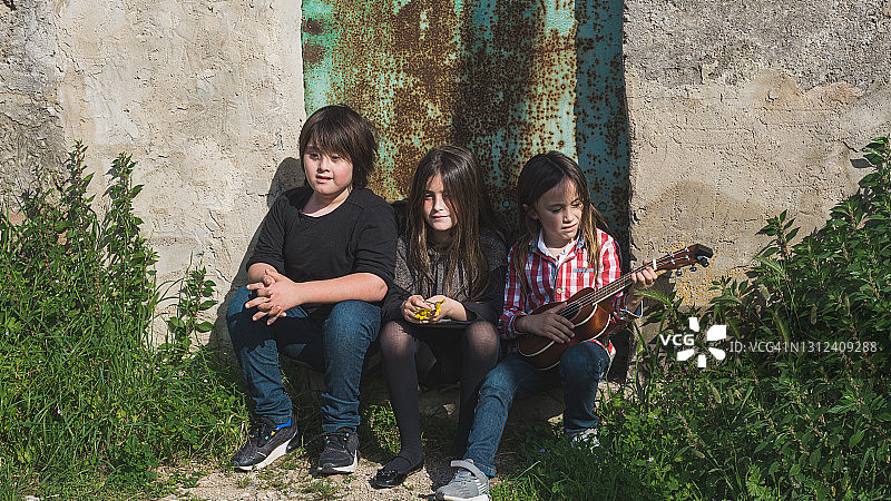 在房子门口休息的三个兄弟姐妹图片素材