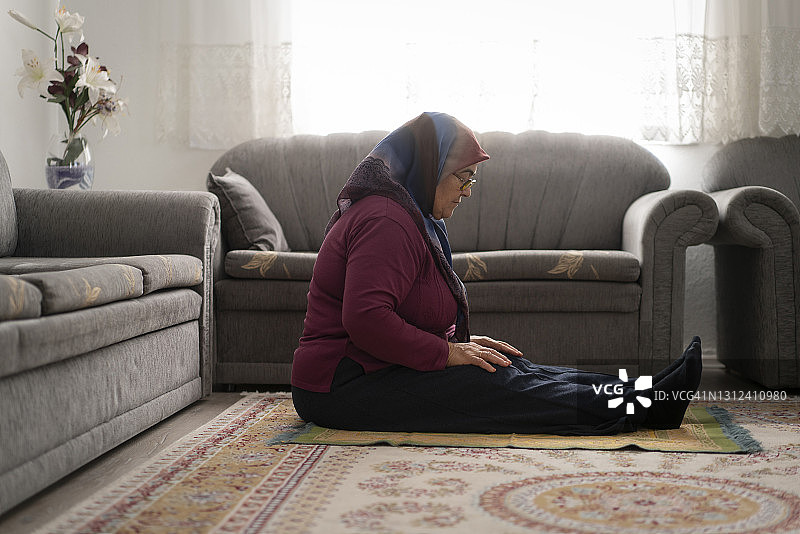 戴头巾的穆斯林老年妇女在家祈祷图片素材