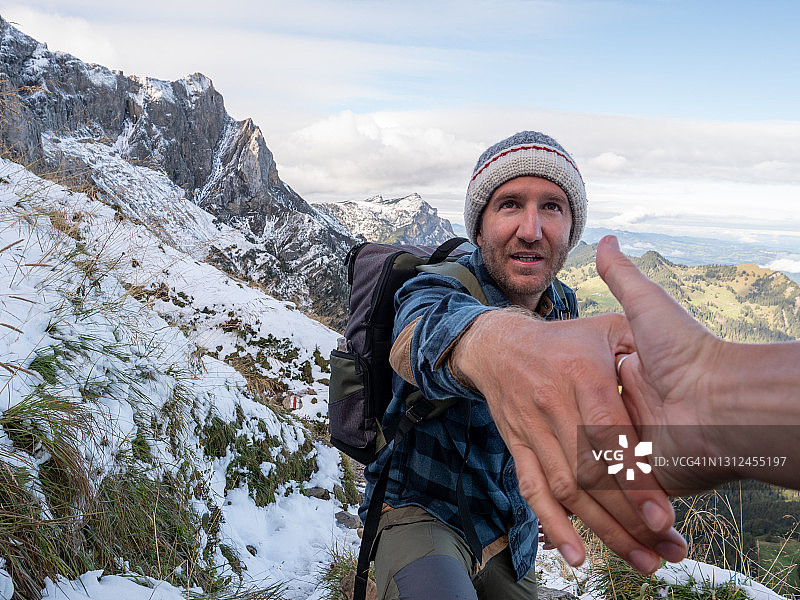 徒步者帮助队友攀登山脊上的岩石图片素材