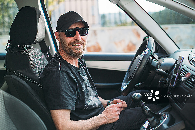 戴着帽子和太阳镜，在车里微笑的络腮胡男人图片素材
