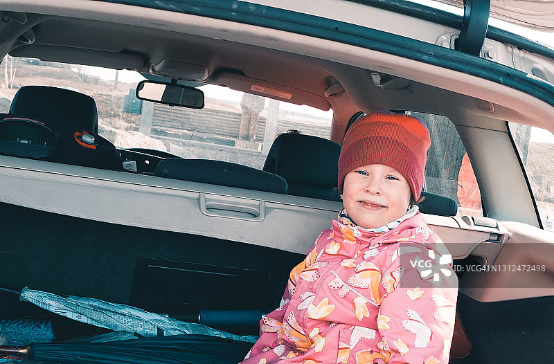 坐在汽车后备箱里微笑的白人女孩图片素材