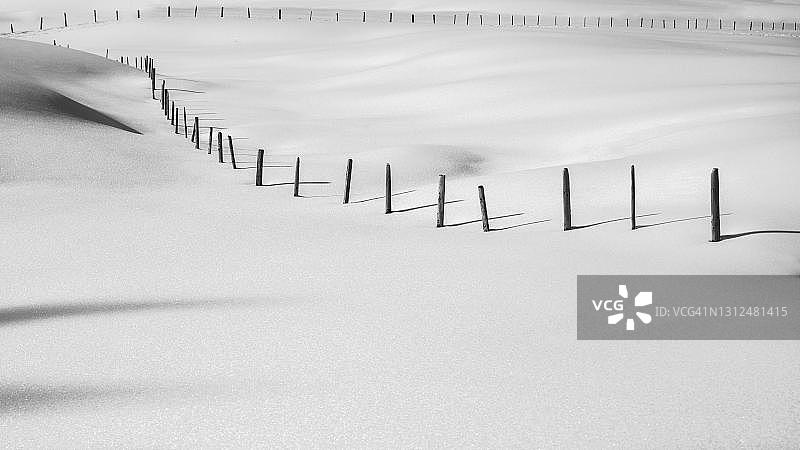巴伐利亚阿尔卑斯山区巴尔德施旺白雪皑皑的草地上的栅栏图片素材