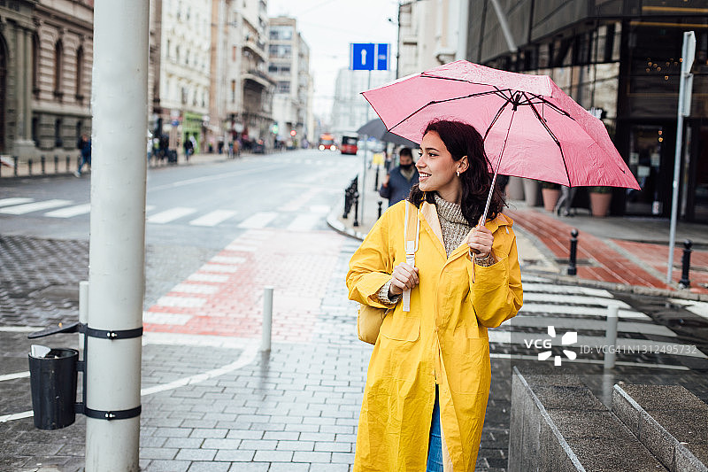 在雨中穿过城市的年轻学生肖像图片素材