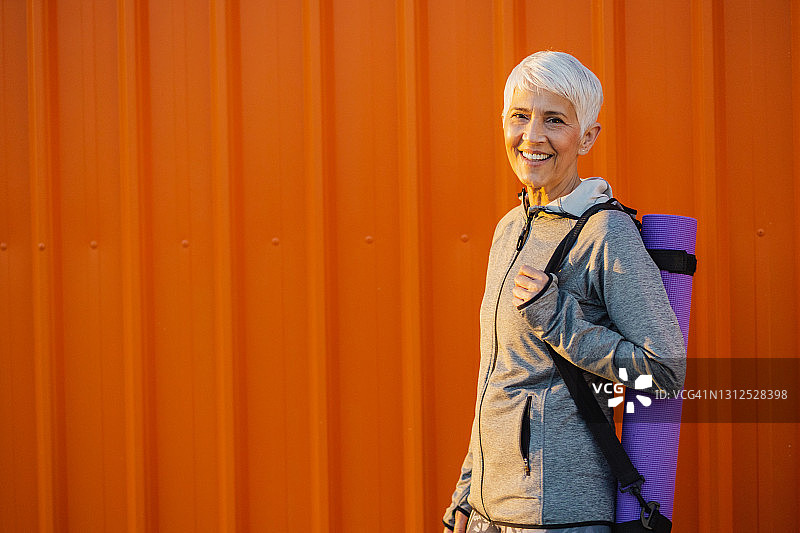 橙色墙前身穿运动服的活力老年妇女肖像图片素材