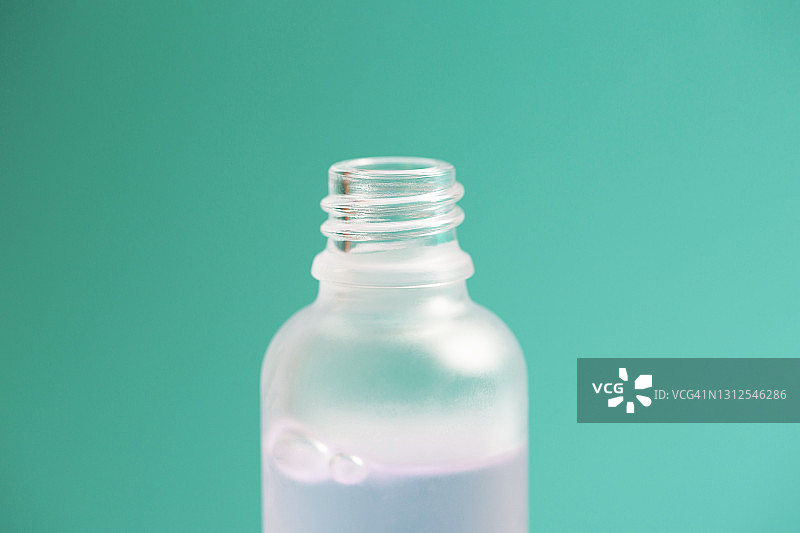 土耳其蓝色背景化妆品凝胶或精华液开启玻璃瓶特写图片素材