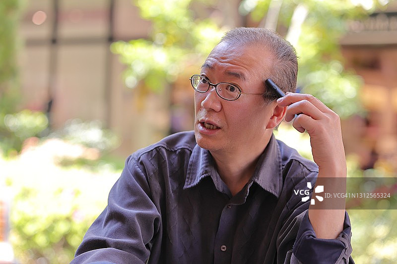 在花园里用智能手机通话的日本中年女人图片素材