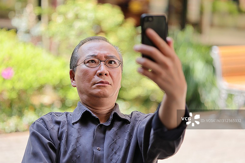 在花园里用智能手机进行视频通话的中年女人图片素材