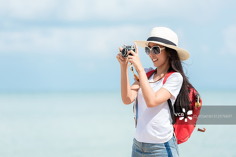 在海滩度假的亚洲年轻女性，手持地图和相机拍照图片素材