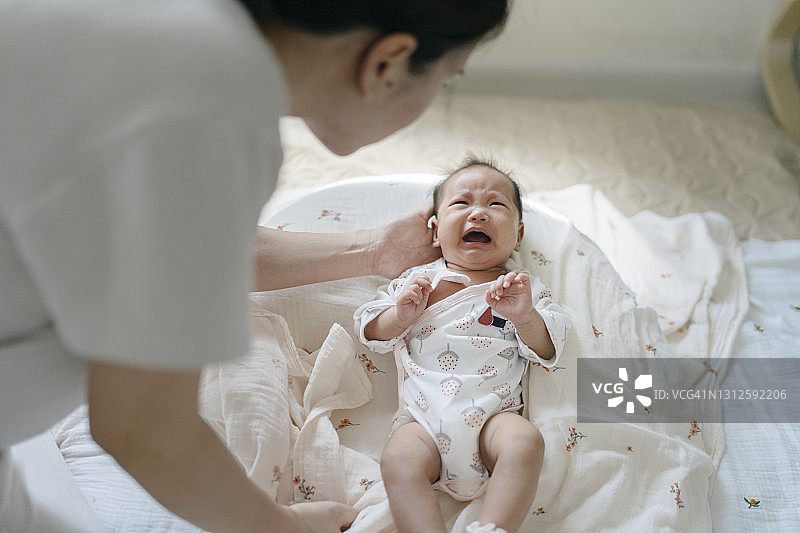 亚洲单身母亲在家安慰哭闹的新生女儿图片素材