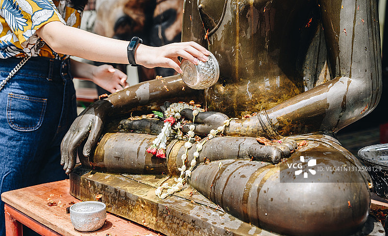特写：泰国泼水节，女人往佛像手上倒香水图片素材