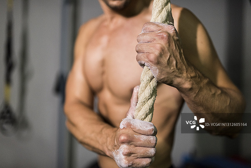 男人在健身房赤膊训练，撒 chalk 或镁粉，以更好地用手抓握图片素材