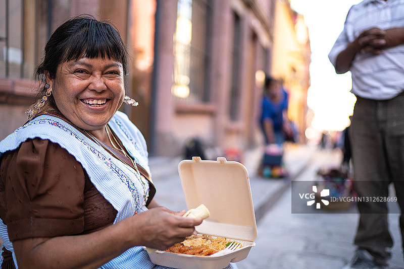 坐在街边吃东西的中年妇女肖像图片素材
