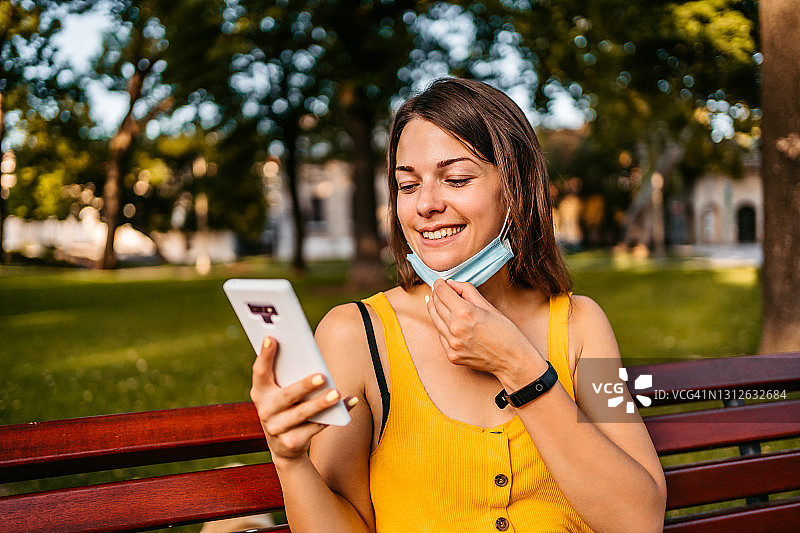 戴着口罩在手机上看社交媒体的女人图片素材