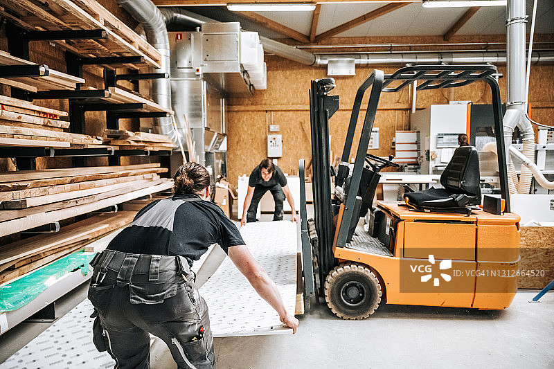 两名工人在木工车间用叉车搬运面板图片素材