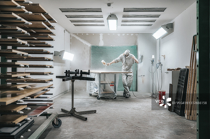 身穿防护服的木匠正在给木板刷清漆图片素材