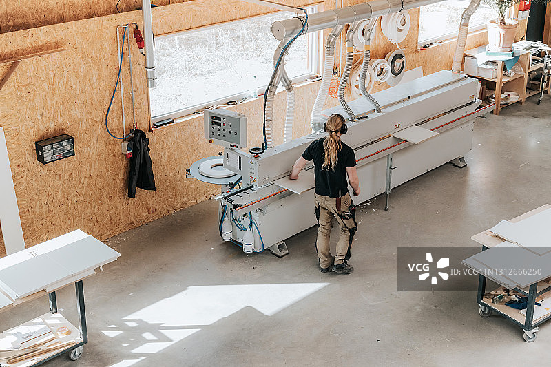 木匠在封边机上层压木板图片素材