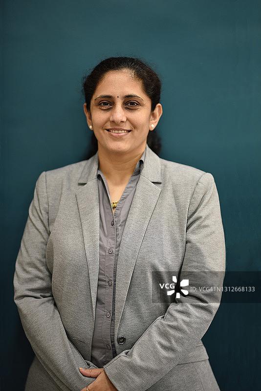 穿着西装的成熟女性正式肖像，蓝色背景图片素材