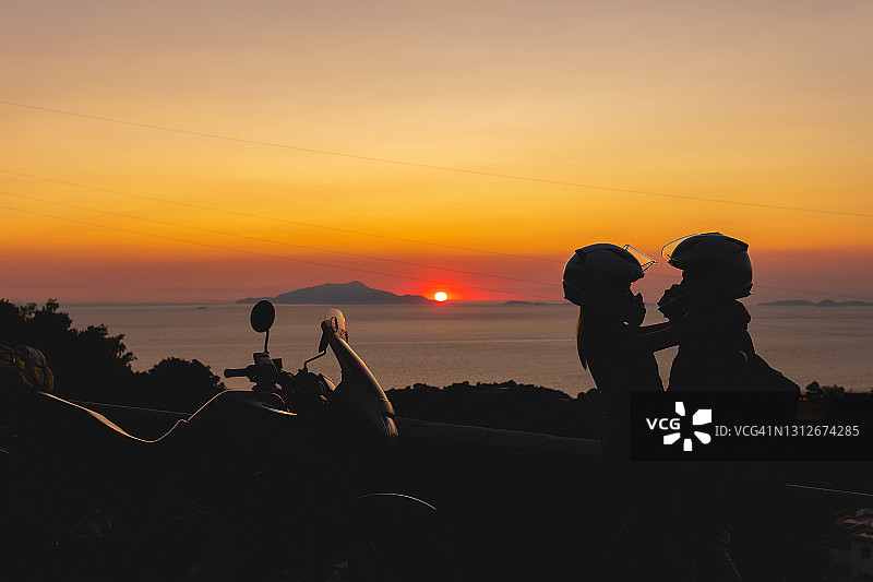 情侣在卡普里岛日落下的摩托车剪影图片素材